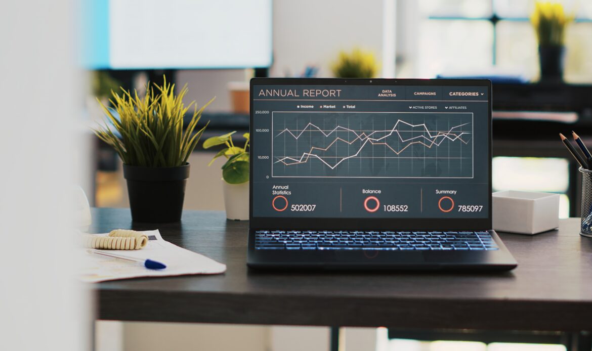 business graphs figures laptop left open desk empty office scaled